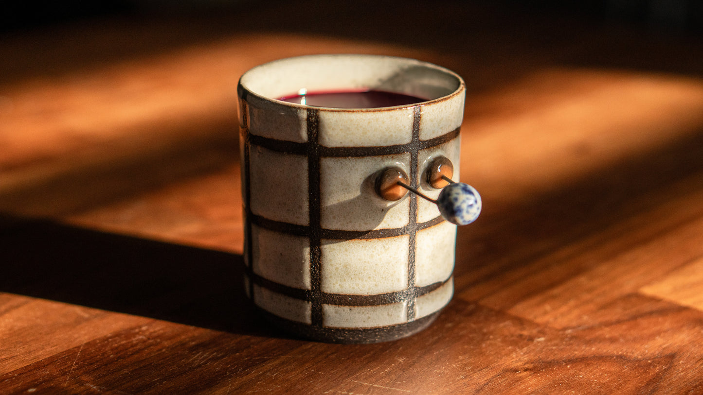 lifestyle shot of white checkered cup with wine in by a hill studio