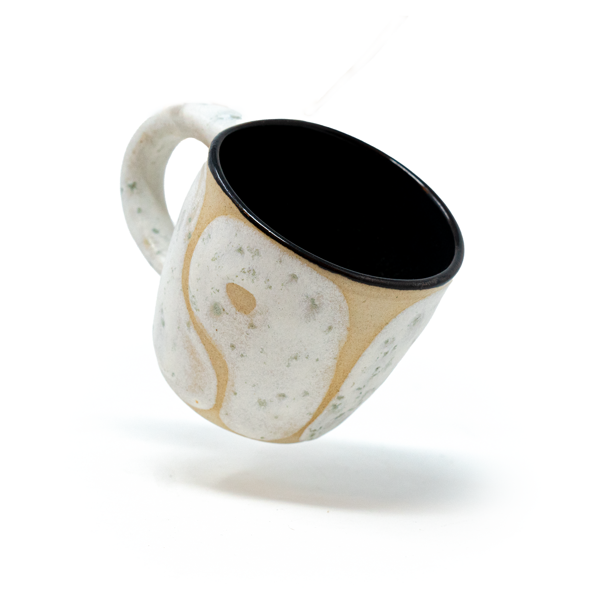 floating cream and white ceramic cup by a hill studio