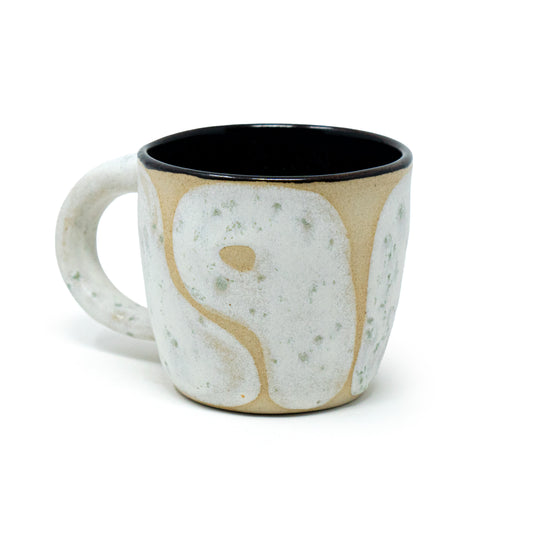 Cream and white ceramic cup by a hill studio