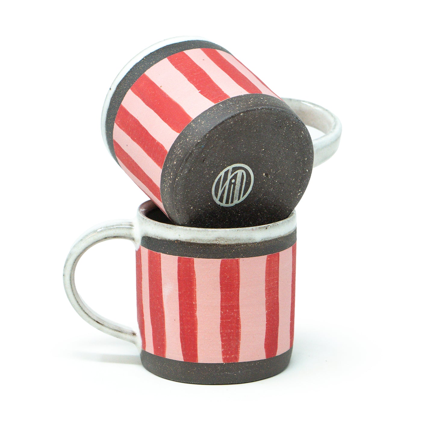Two ceramic mugs with red and pink striped pattern and black base on a white background