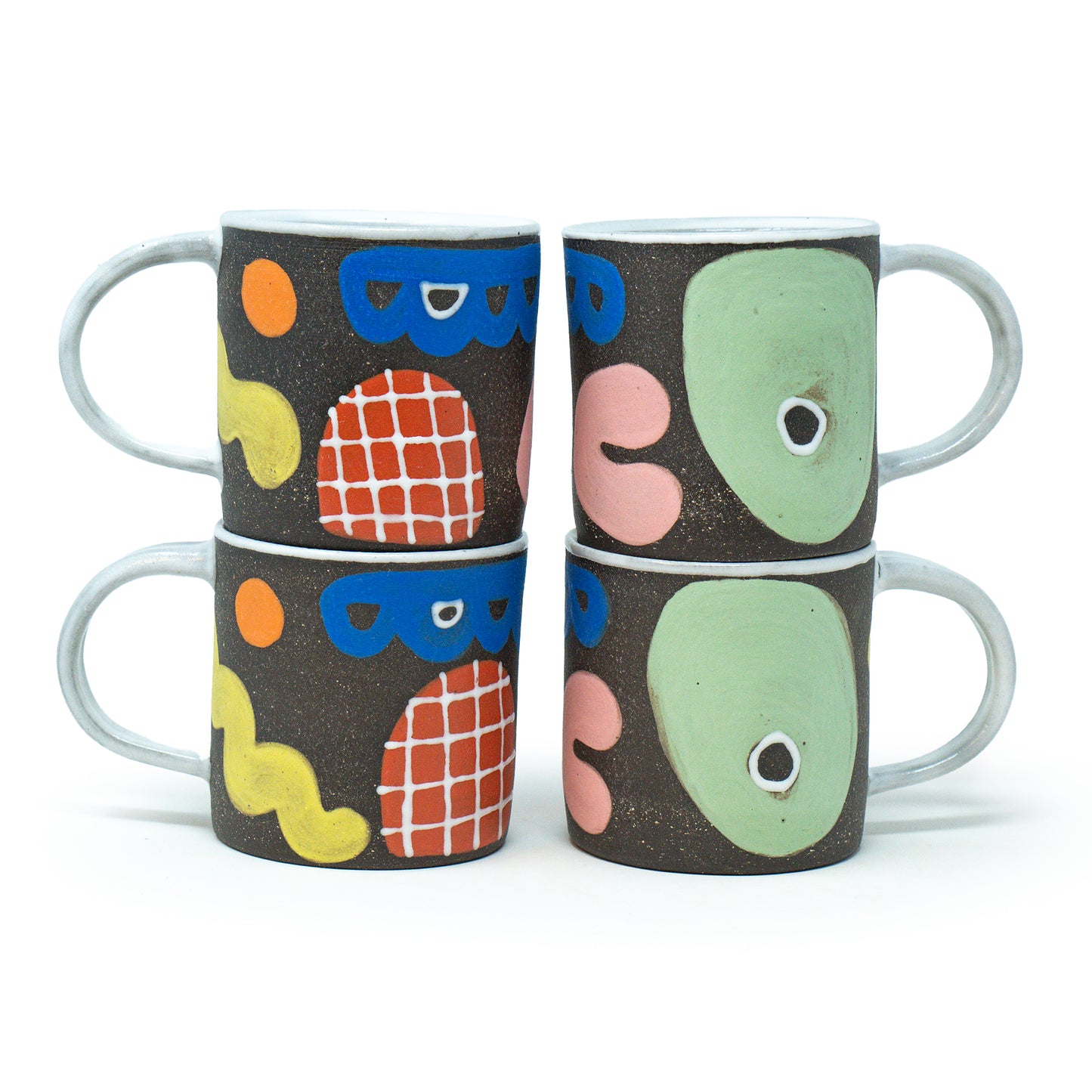 Four ceramic mugs with colorful abstract designs on a white background