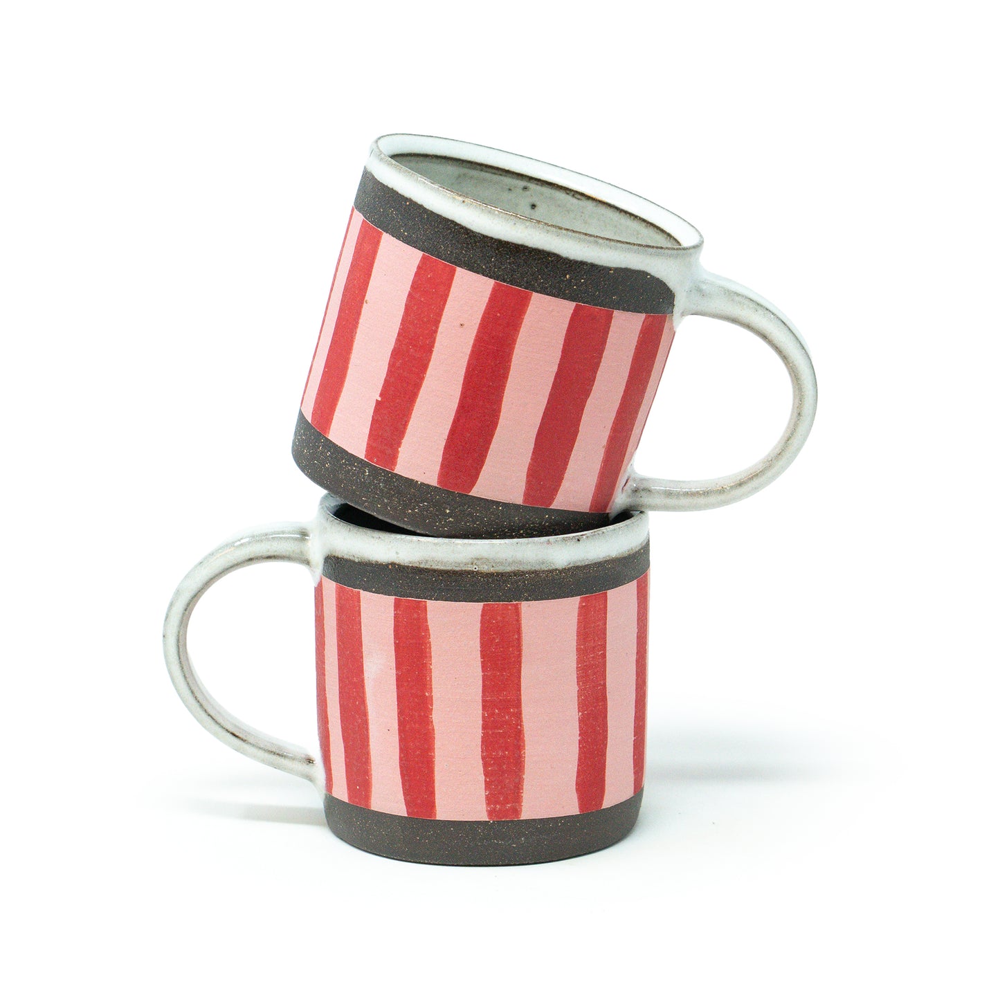 Two ceramic mugs with red and white striped design stacked on a white background