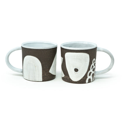 two winter solstice mugs side by side 